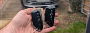 Two VW Golf smart keys held in a hand in front of a 2025 Mk8 Golf, Keycraft Auto Locksmiths